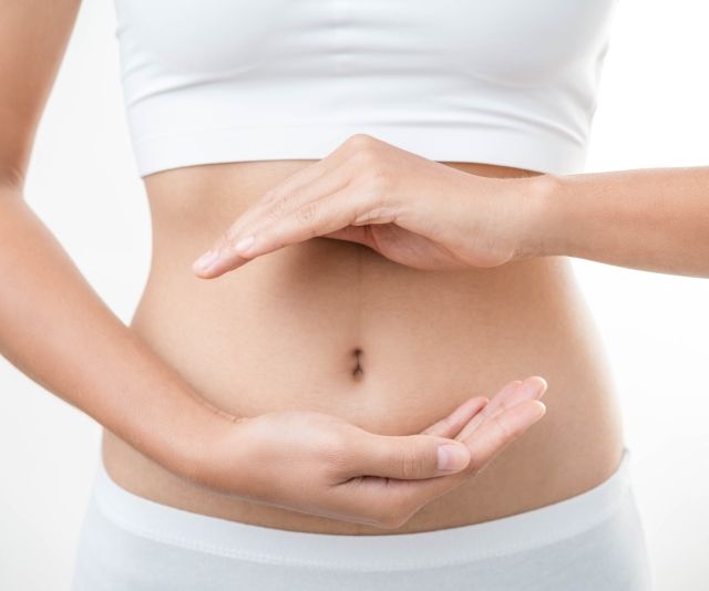 Frau hält Hände über ihren Bauch